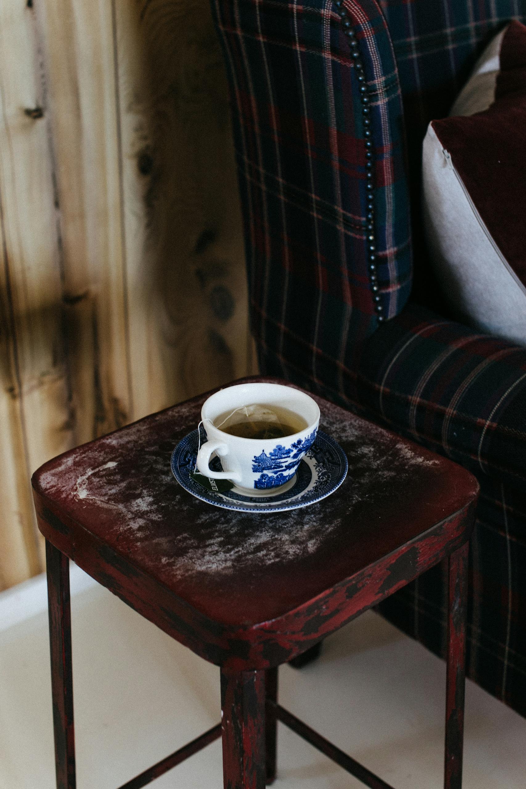 Rustic indoor setting featuring a hot tea cup on a vintage stool, perfect for a cozy morning.