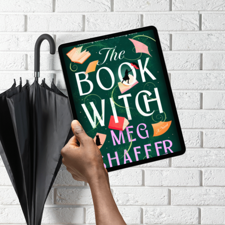 A black umbrella leaning on a white brick wall with a person's hand holding up an ereader with a book title of the book witch by meg haffer